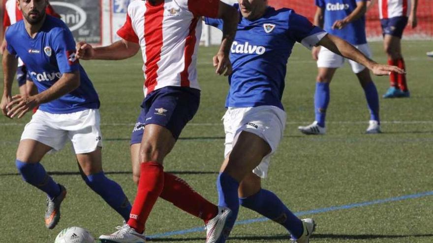 Un jugador del Alondras conduce el balón ante la presión de dos rivales. // Santos Álvarez