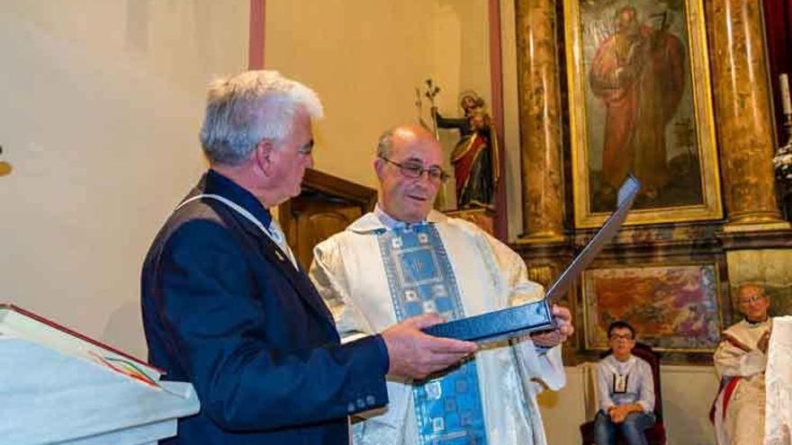 El antiguo párroco, José Manuel Ramos, recibe la placa de la cofradía de la Virgen del Carmen.