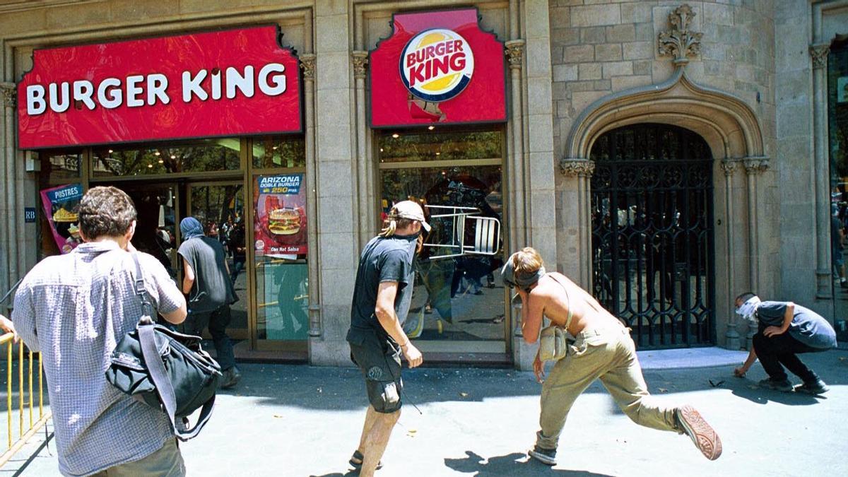 Un grupo de afines al movimiento antiglobalización y organismos como el Banco Mundial atacan el establecimiento de una cadena de comida rápida situado en el centro de la ciudad de Barcelona, el 24 de junio de 2001.