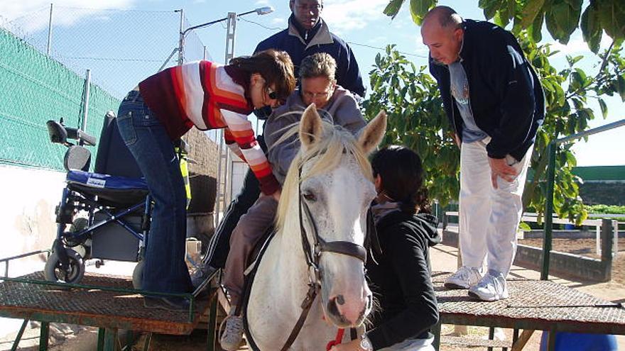 Preparativos. Una de las participantes en el programa de terapia ecuestre es ayudada a montar en el caballo.