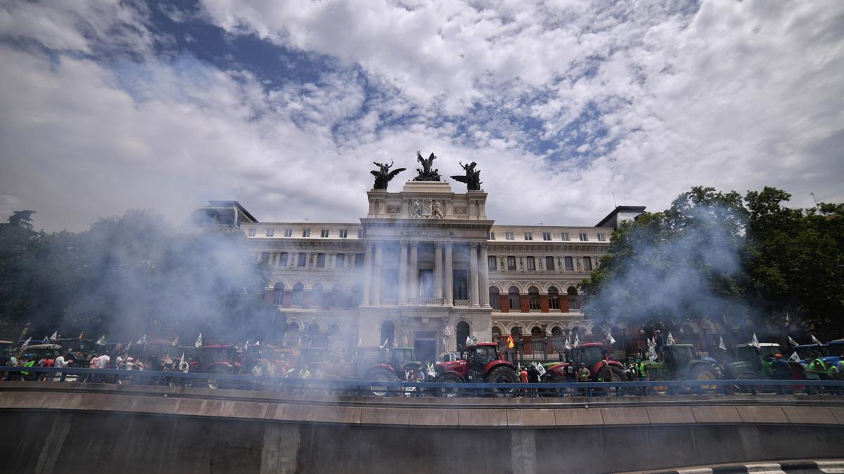 Los tractores que participan en una tractorada convocada por la Unión de Uniones de Agricultores y Ganaderos, tiran petardos frente al Ministerio de Agricultura.