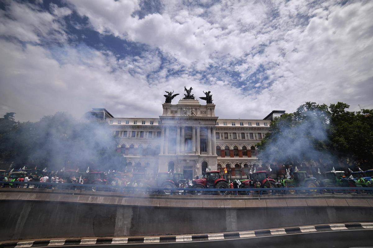 Los tractores que participan en una tractorada convocada por la Unión de Uniones de Agricultores y Ganaderos, tiran petardos frente al Ministerio de Agricultura.
