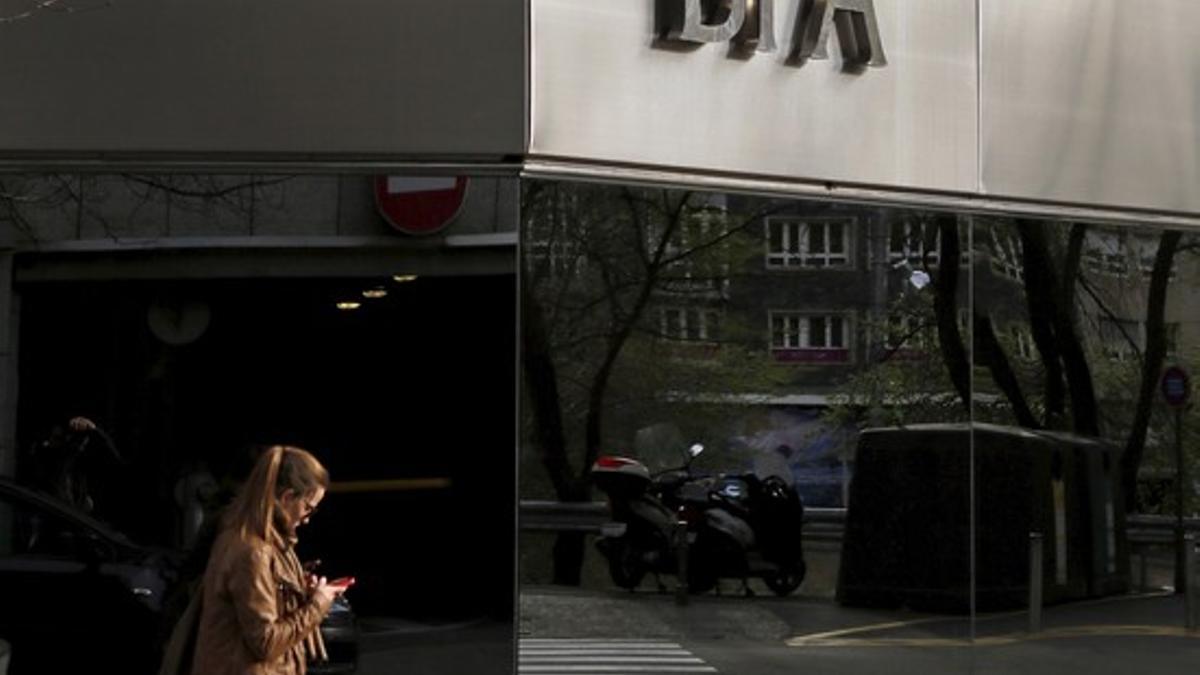 A woman looks at her mobile phone as she walks past a BPA office in Andorra la Vella