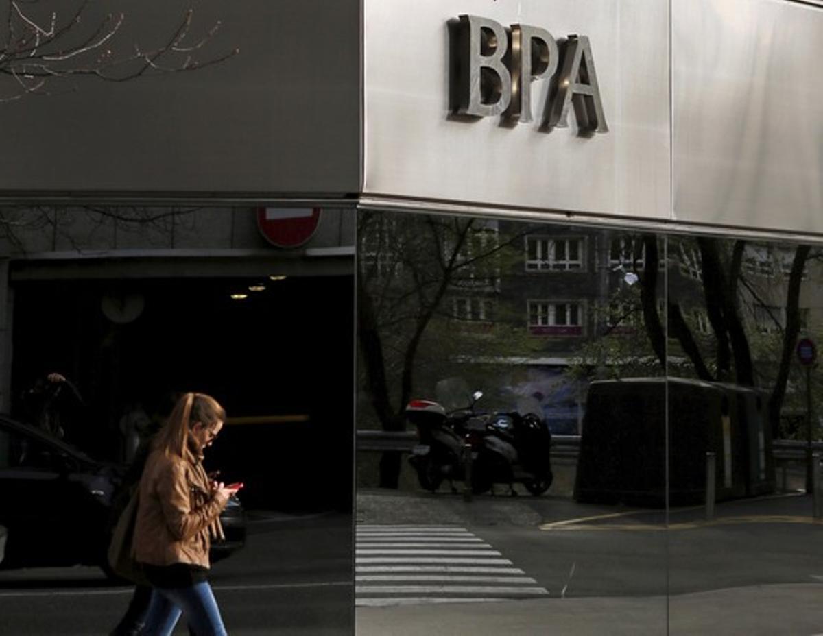 A woman looks at her mobile phone as she walks past a Banca Privada d Andorra  BPA  office in Andorra la Vella March 29  2015  Andorra will create a  bad bank  to group the assets of BPA linked to illicit activity  it said late on Thursday  as the principality battles to rebuild the reputation of its banking system  REUTERS Albert Gea