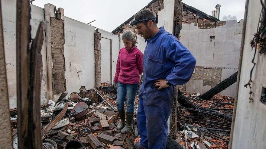 Dos vecinos de la localidad ourensana de Melón en el interior de su vivienda calcinada por las llamas.
