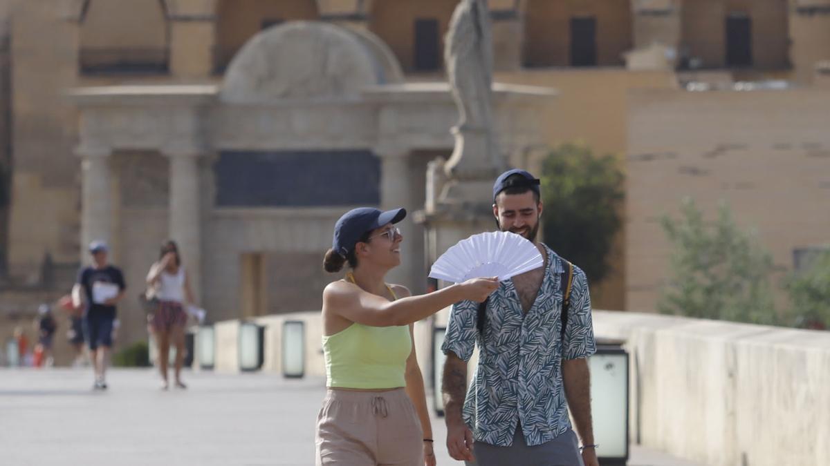 Unos turistas, por el Puente Romano, desafiando al calor cordobés.