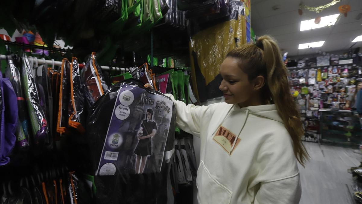 Una joven mirando el disfraz de Miércoles Adams en la tienda de disfraces Bacanal.