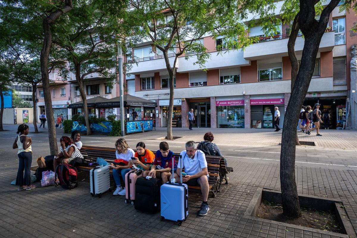 Turistas esperando con sus maletas delante de un bloque de pisos turísticos en Barcelona.