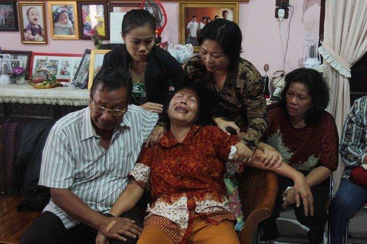 Una dona és consolada pels seus familiars, a casa seva de Medan, a Indonèsia.