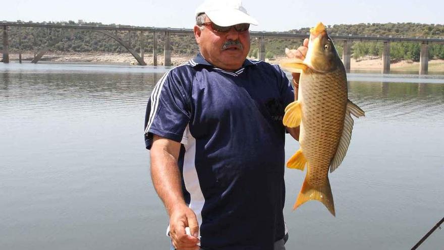 Un pescador muestra una carpa capturada en el embalse de Ricobayo.