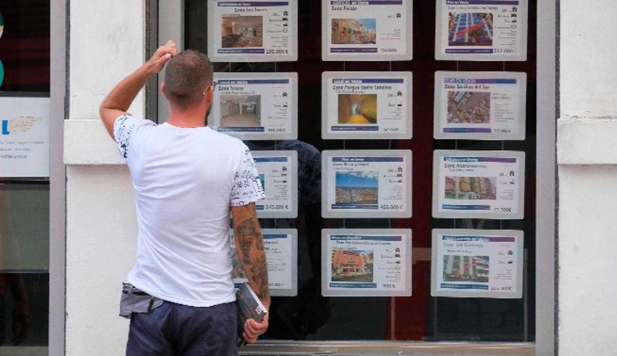 Un ciudadano observa las ofertas en el escaparate de una agencia inmobiliaria.