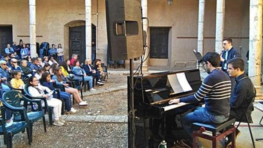 El público disfruta de la actuación de un alumno, acompañado al piano por un profesor del centro.