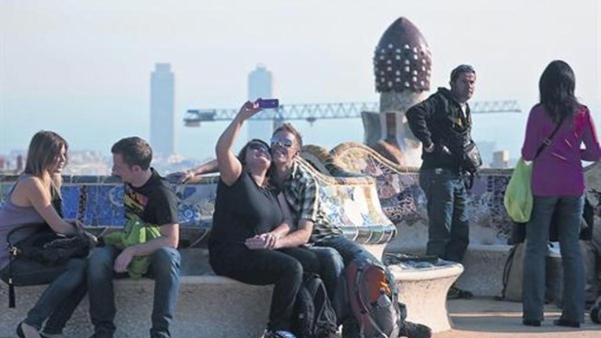 Una pareja de turistas se fotografía en uno de los bancos del parque Güell, ayer.