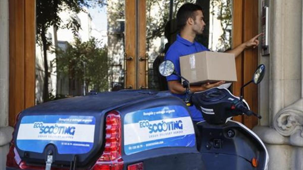 REPARTOUn trabajador de Ecoscooting entrega un paquete con su vehículo eléctrico.