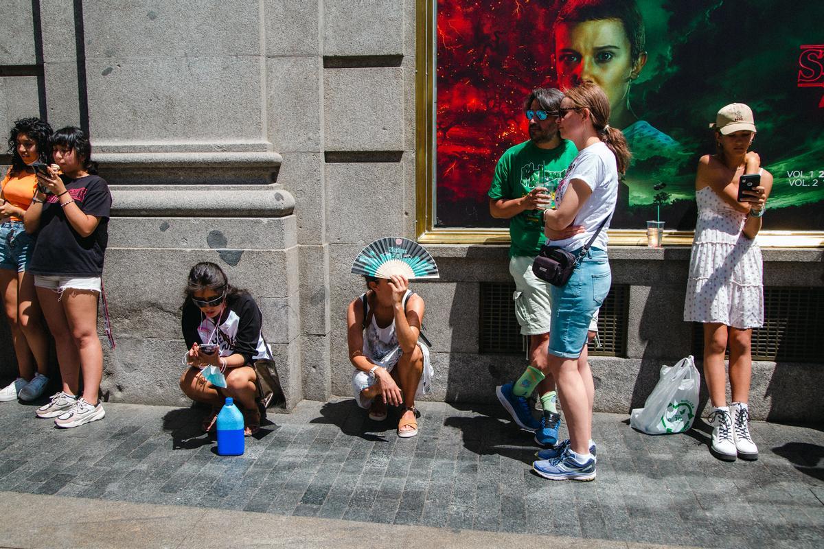 Fans de Stranger Things sentados en la acera durante la espera para ver la experiencia inmersiva de Stranger Things.