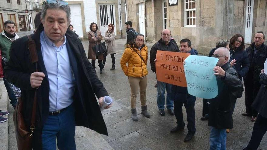 El alcalde, Miguel Lores, pasa ante un grupo de vecinos de Monte Porreiro que protestó contra el plan del compostaje en el pleno. // R.V.