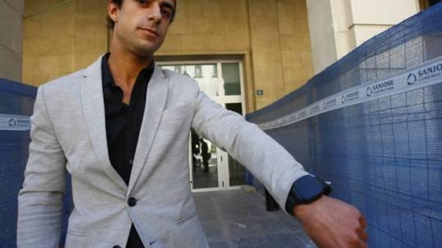 Fernando ayer frente a la Audiencia enseña la pulsera telemática que tiene que llevar.