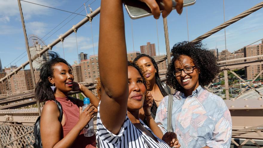 Varias personas se toman un 'selfie' con un teléfono móvil.
