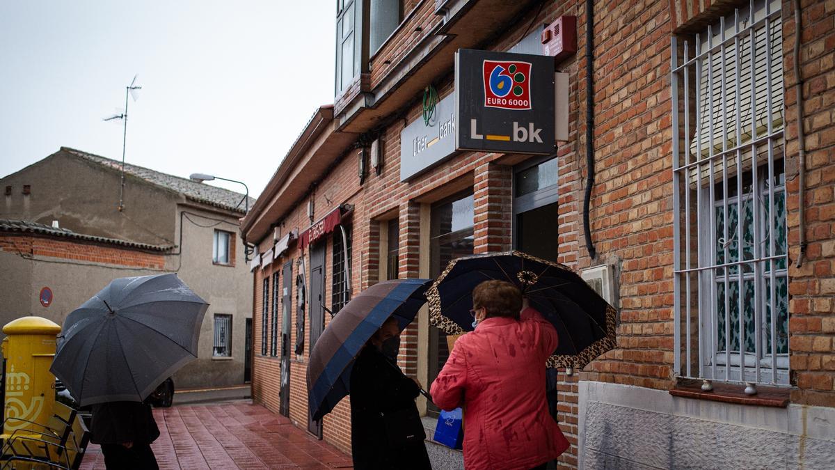 Varios vecinos de Alcabón, en Toledo, esperan frente a una sucursal bancaria de la localidad.