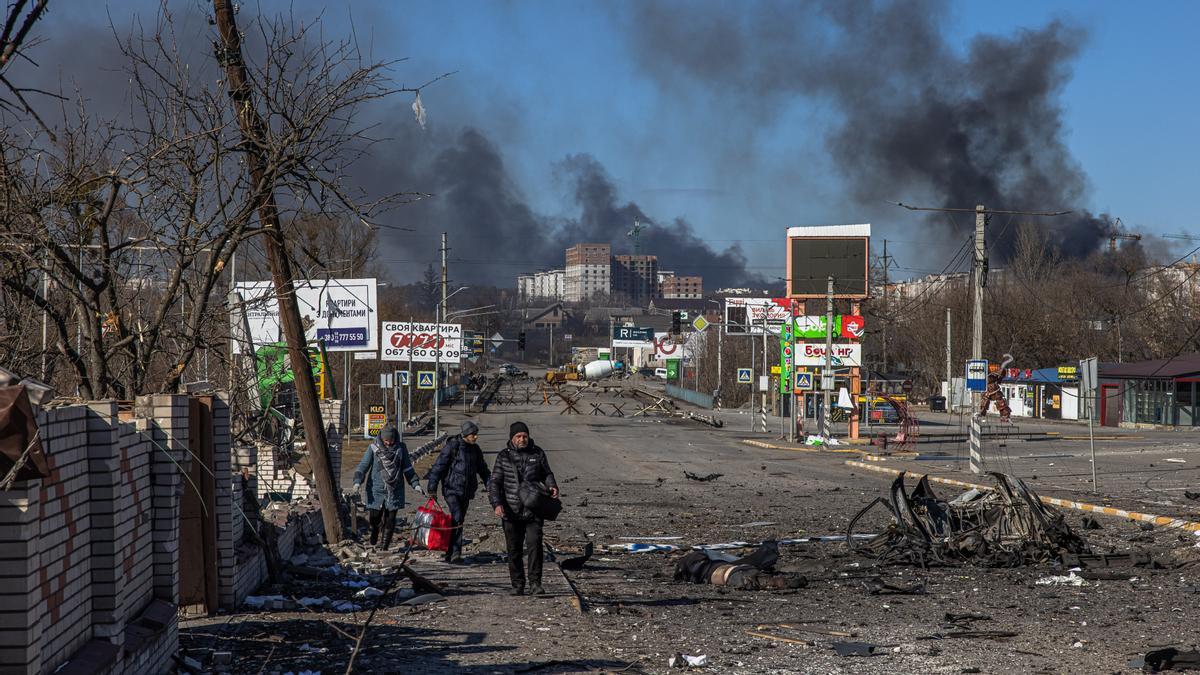 Las personas que vienen de la ciudad de Bucha, que actualmente está controlada por el ejército ruso, caminan con equipaje más allá del cuerpo de un hombre muerto hacia el puesto de control ucraniano, en la línea del frente en la ciudad de Irpin, región de Kiev, Ucrania, 10 de marzo de 2022