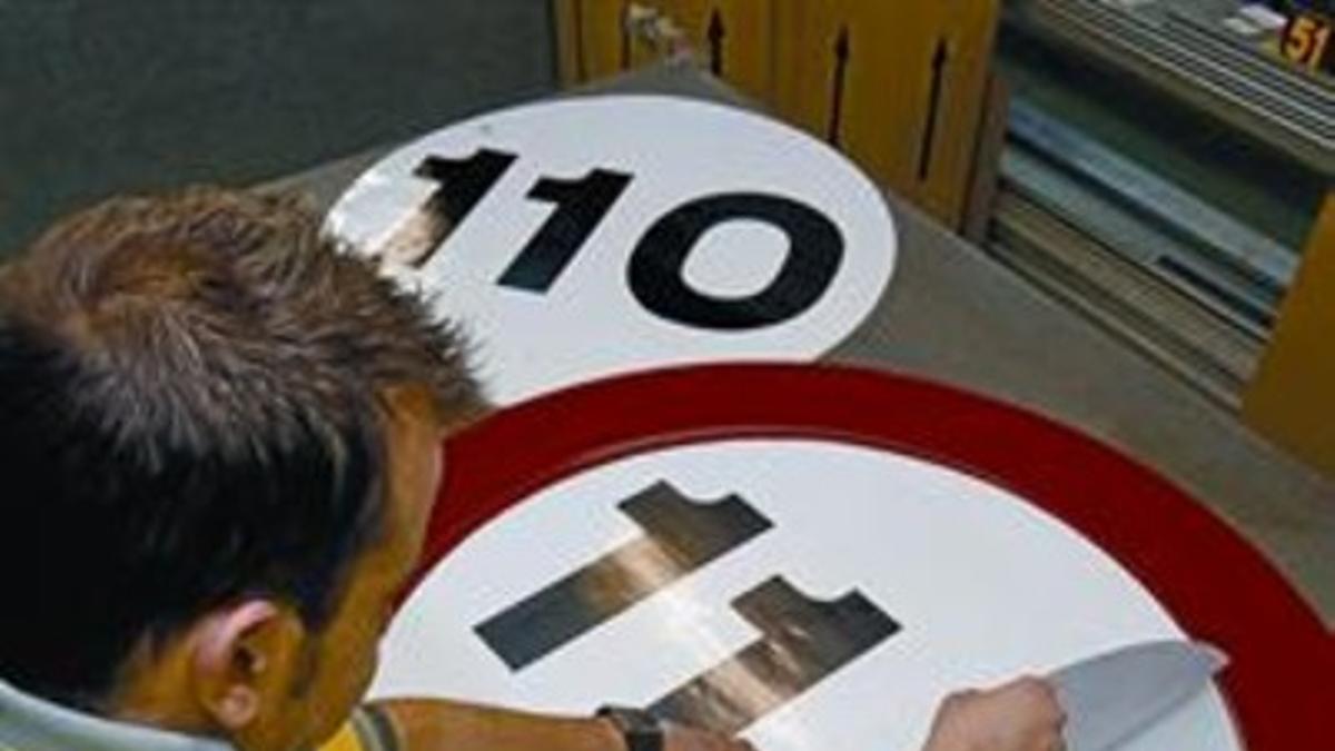 Un empleado de Proseñal pega el límite de velocidad que regirá a partir del lunes a una señal.