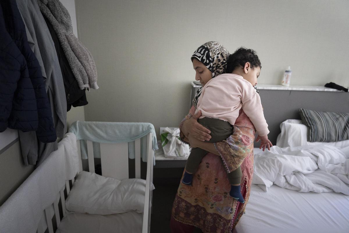 La mujer de Muhammad, Dua Fatima, sostiene su hija de poco más de un año en una habitación de un hostal donde viven tras acabar el congreso del móbil.