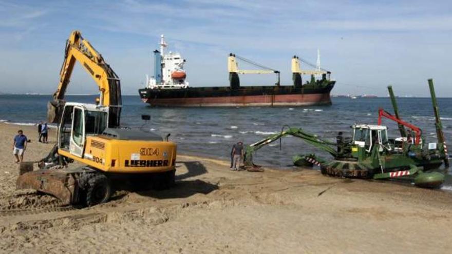 Imagen de la draga trabajando ayer en el Saler para tratar de desencallar al buque atrapado frente a la costa.