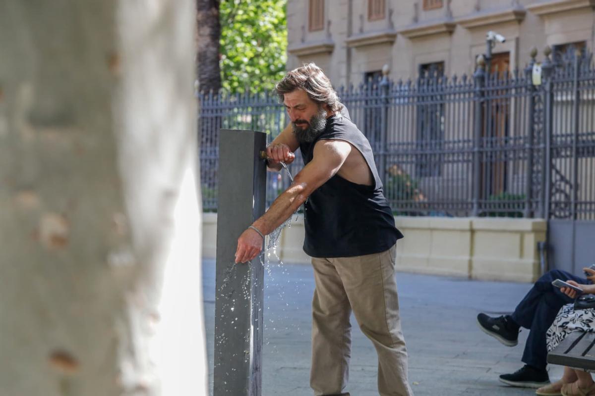 Un hombre se refresca en una fuente de la plaza Aragón de Zaragoza