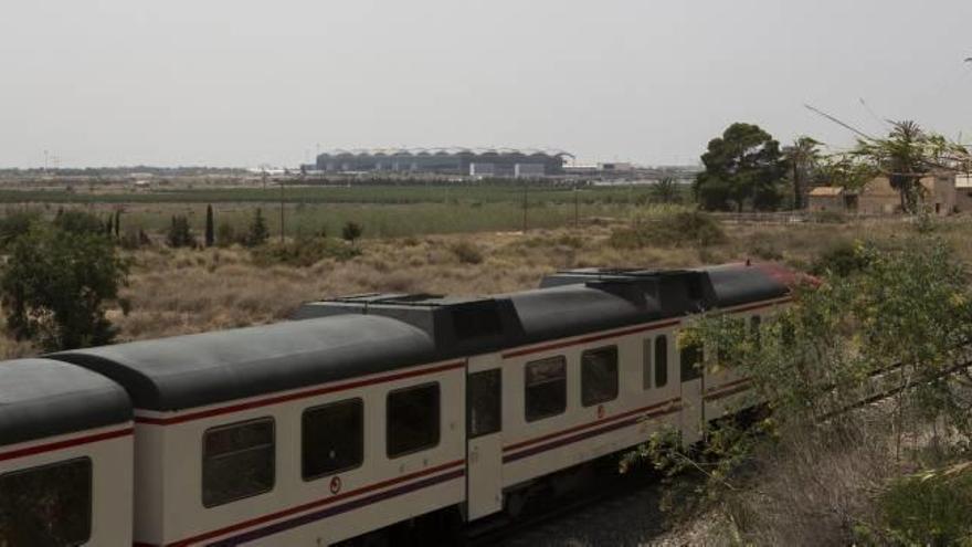 El tren de cercanías Alicante-Elche a su paso por las Casas de Bonmatí, en el límite entre Alicante y Elche. Al fondo, la terminal del aeropuerto.
