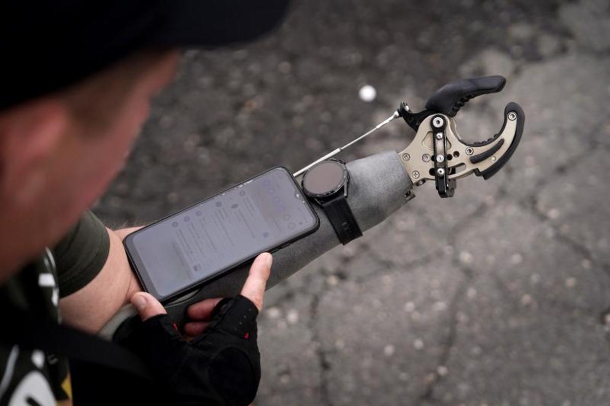 Un excombatiente mutilado ucraniano sujeta su móvil en su brazo artificial durante una vistia a Madrid