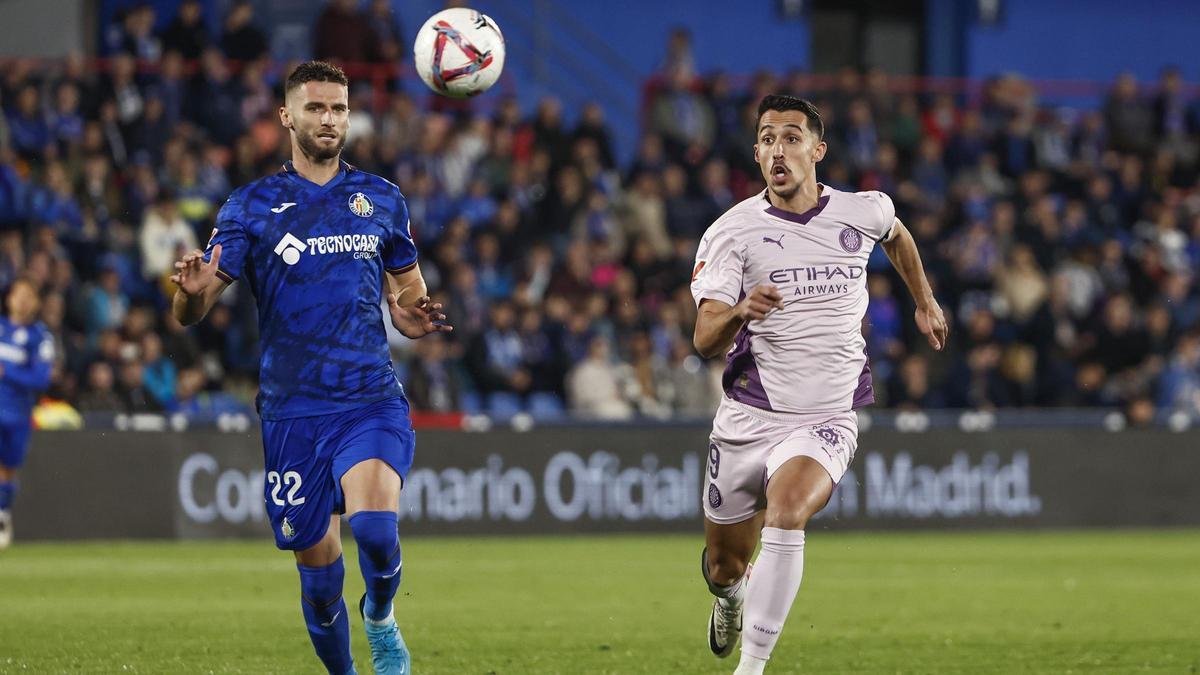 Duarte, the Getafe defender, and Miovski, ​the Girona striker, are fighting ‍for ‌the ⁢ball at the Coliseum Alfonso Pérez.