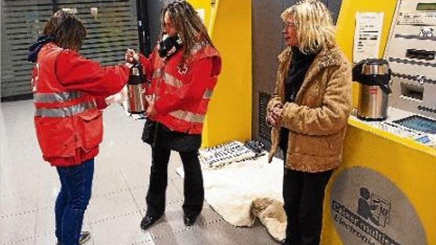 Voluntaris de Creu Roja van oferir mantes, menjar i begudes calentes a les persones que viuen al carrer.