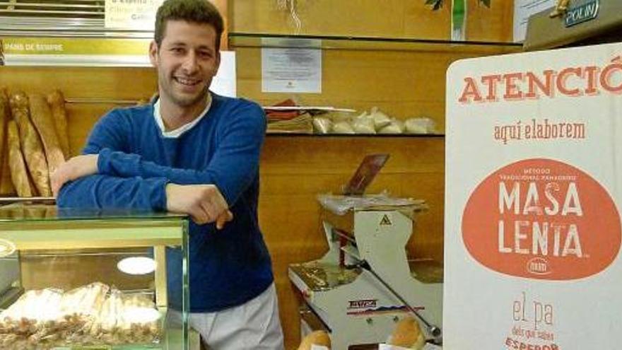 Marc Aracil al seu forn, a Igualada, amb els cartells de promoció del nou pa