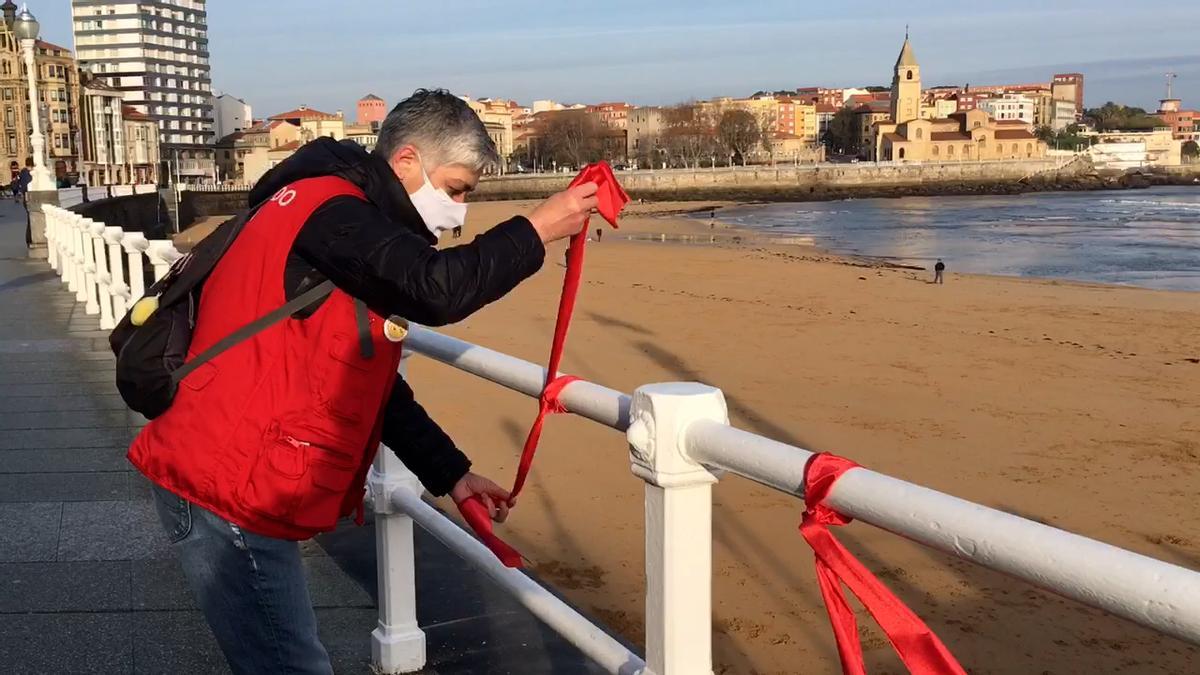 Un voluntario coloca unos lazos en el paseo del Muro