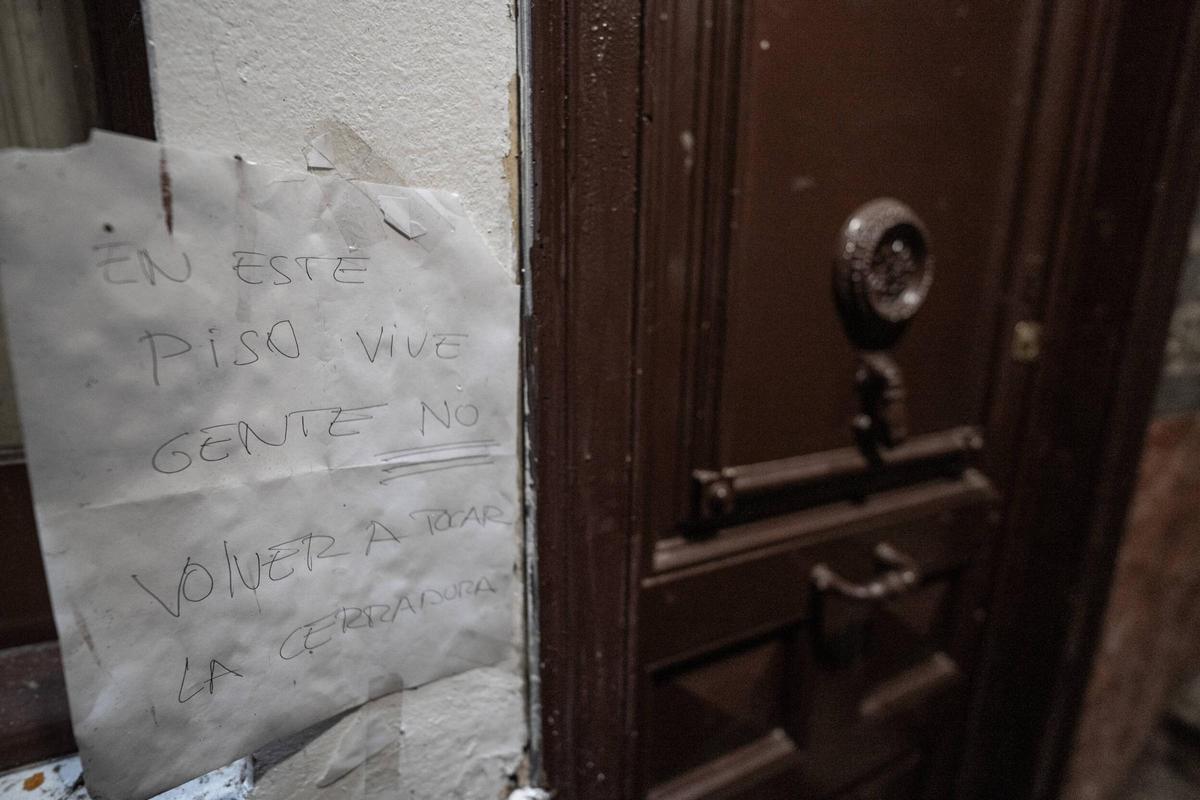 Un cartel de aviso en la escalera del edificio que acumula denuncias en el pasaje Alió, en Barcelona.