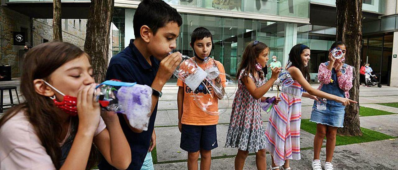 Niñas y niños hacen pompas de jabón con una botella reciclada.