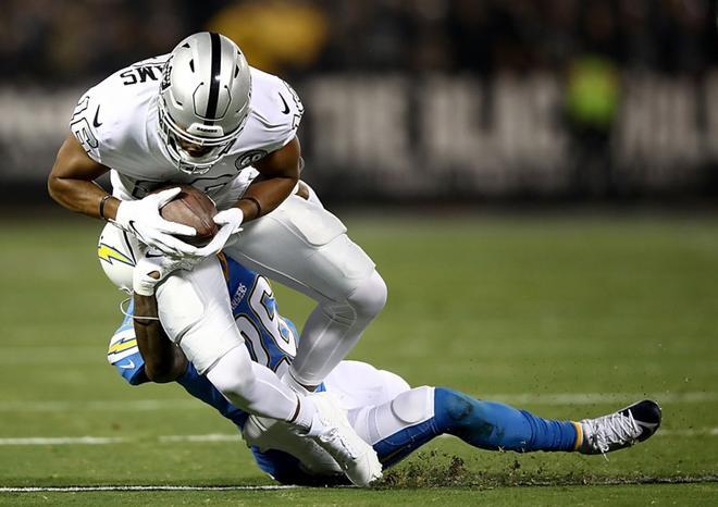 El receptor abierto Tyrell Williams # 16 de los Oakland Raiders es abordado por el esquinero Casey Hayward # 26 de los Chargers de Los Ángeles durante el primer trimestre en el RingCentral Coliseum.