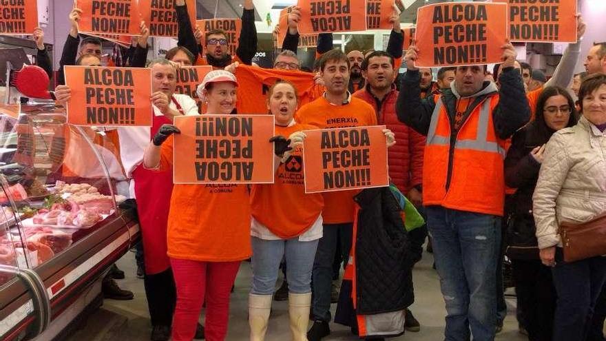 Trabajadores del mercado de Elviña y de Alcoa muestran pancartas contra el cierre de Alcoa ayer.