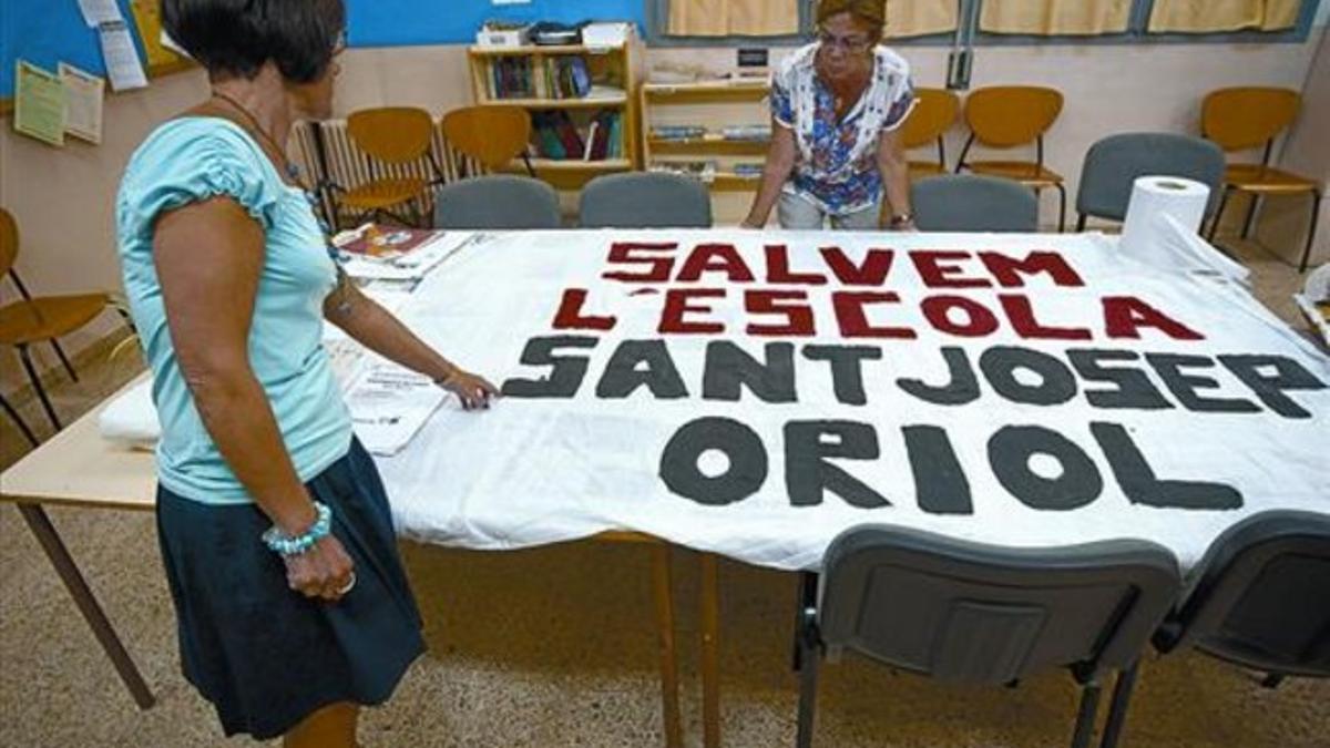 Profesoras de la escuela Sant Josep Oriol, en el distrito, con una pancarta en defensa del centro, este verano.