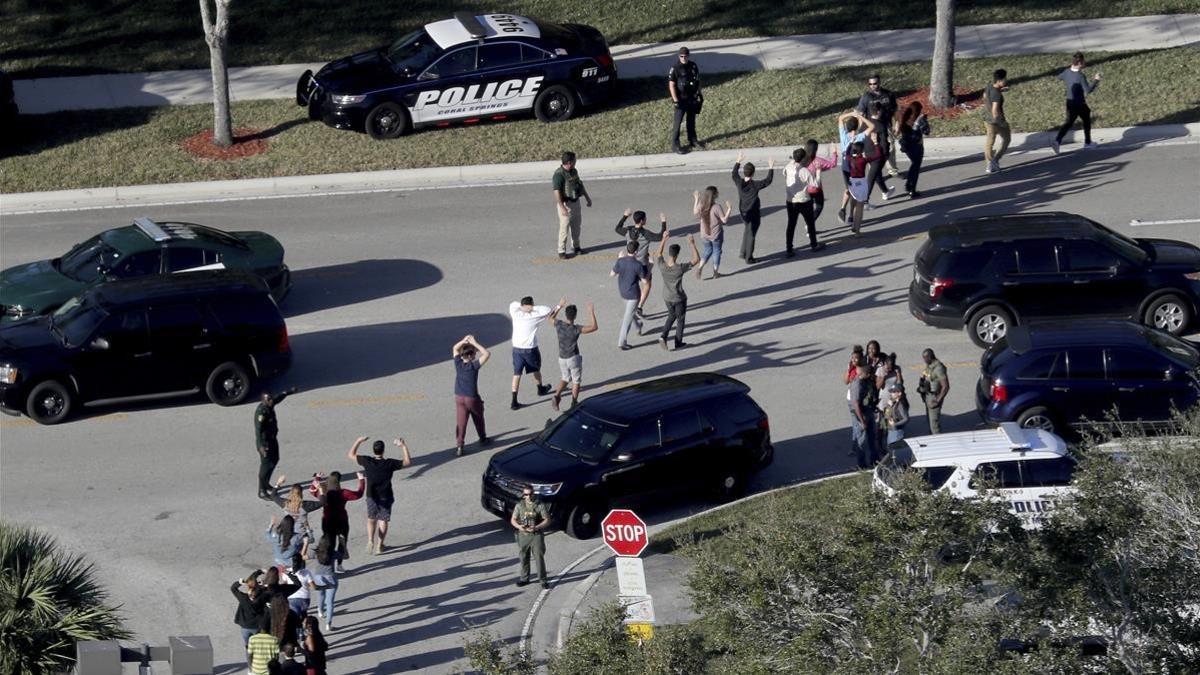 Evacuación de estudiantes con los brazos en alto a la salida del instituto Marjory Stoneman Douglas, en Parkland (Florida), el 14 de febrero.