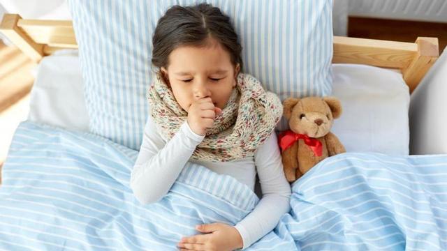 Una niña con tos acostada en su cama. | INGIMAGE