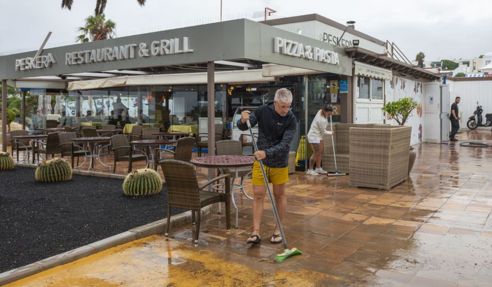 Empleados de un restaurante de Costa Teguise barren el agua que se acumula junto a su negocio. | Efe