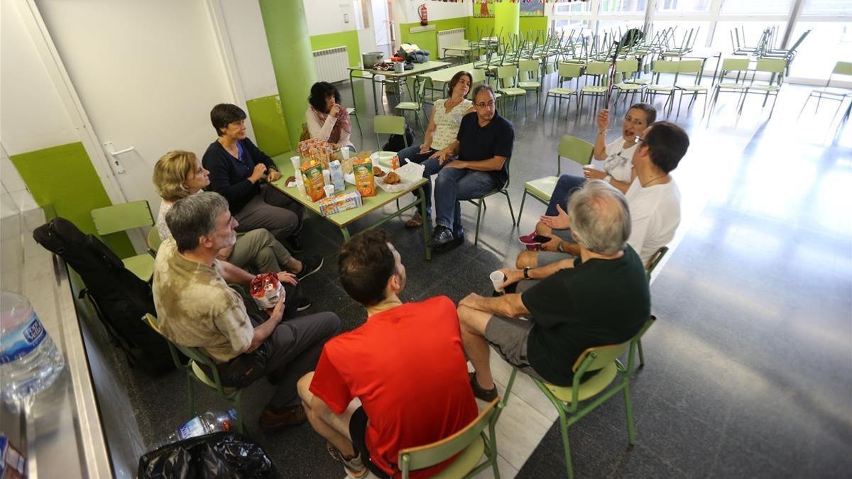 Las personas que han pasado la noche en la escuela Tabor, de Barcelona, desayunando.