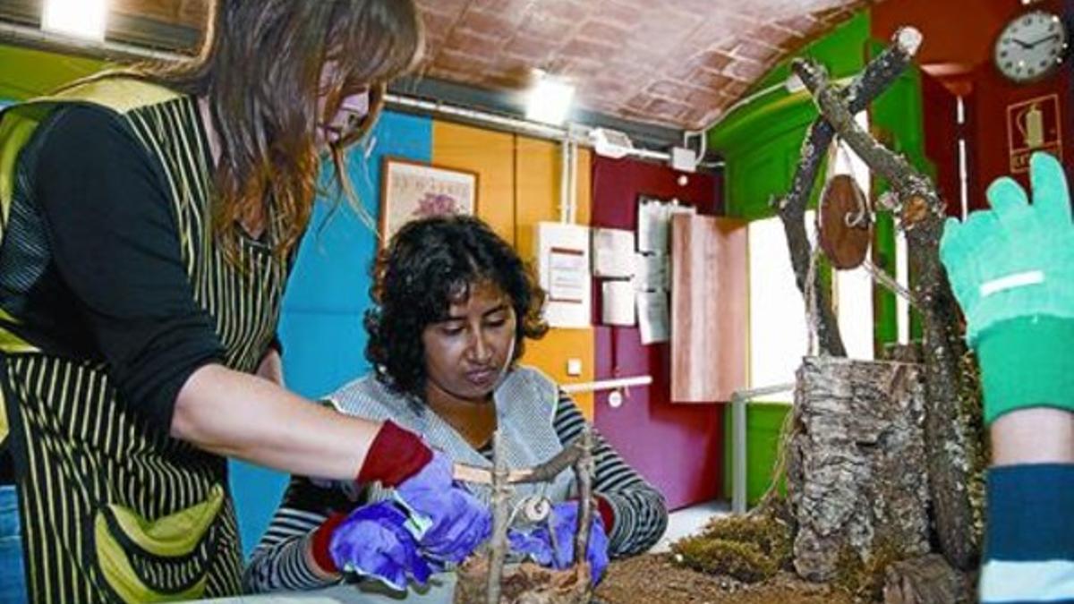 Centro de la fundación 8 Montse Ayola, auxiliar de la entidad, ayuda a una alumna a preparar un belén.