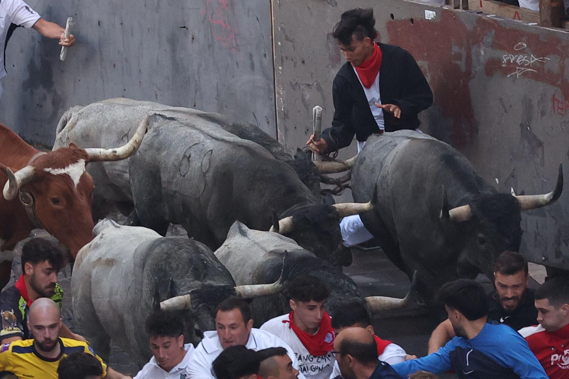 PAMPLONA, 12/07/2025.- Mozos perseguidos por los toros de la ganadería de José Escolar en el tramo inicial de la Calle Estafeta desde la curva de Mercadere,s, en el sexto encierro de los Sanfermines, este sábado en Pamplona. EFE/J.P. Urdiroz