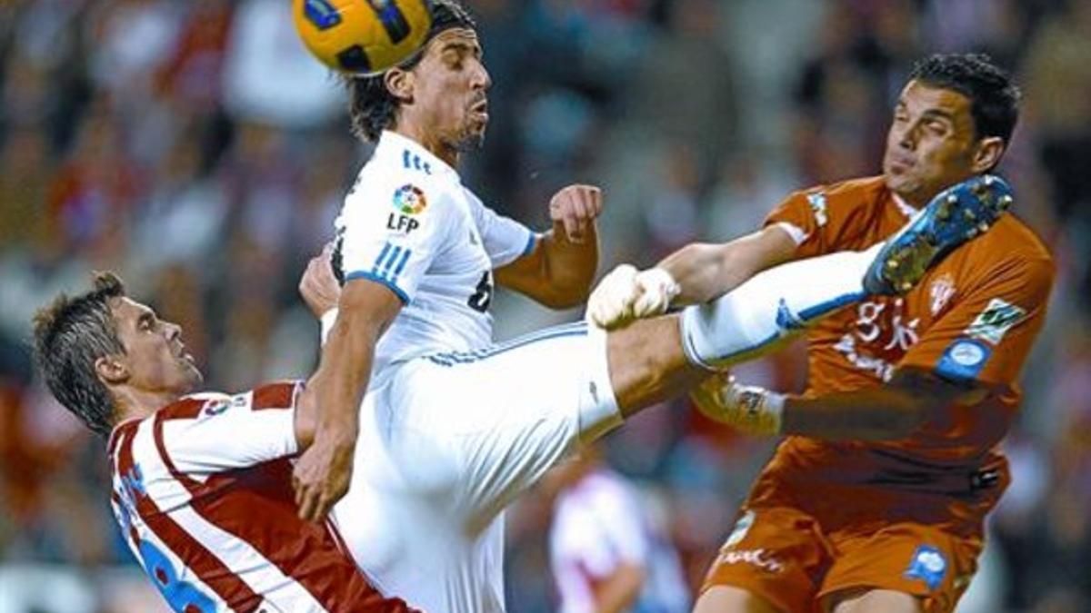 Khedira salta entre el portero Juan Pablo y Sangoy, ayer por la tarde en el estadio de El Molinón.