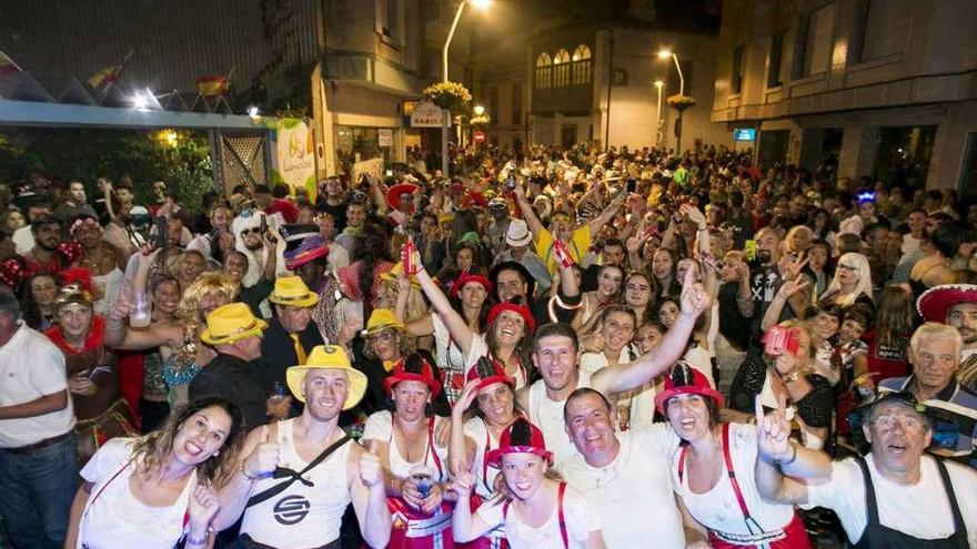 Un nutrido grupo de personas participa en el Antroxu estival en una céntrica calle de Luanco.