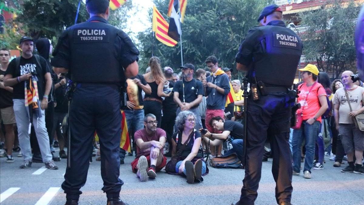 Dos mossos, ante un grupo de manifestantes que organizó una sentada ante la sede de la Guardia Civil en la Travessera de Gràcia de Barcelona, el pasado día 20.