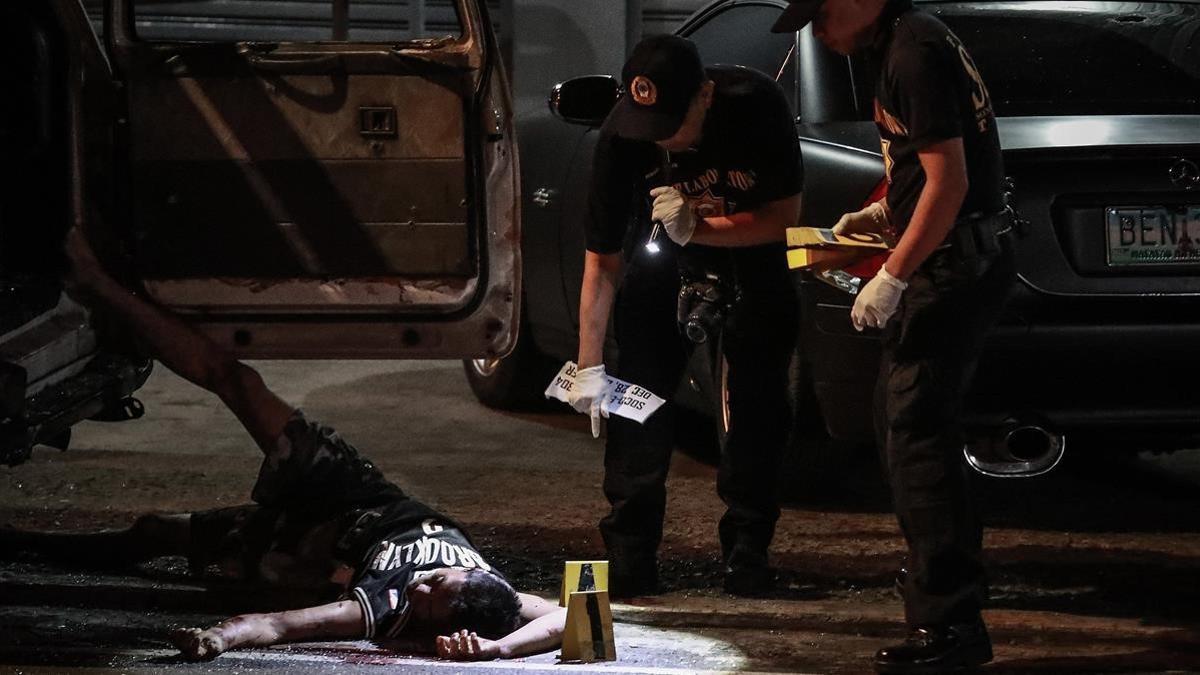 Un cadáver junto a un vehículo acribilladoen Manila.