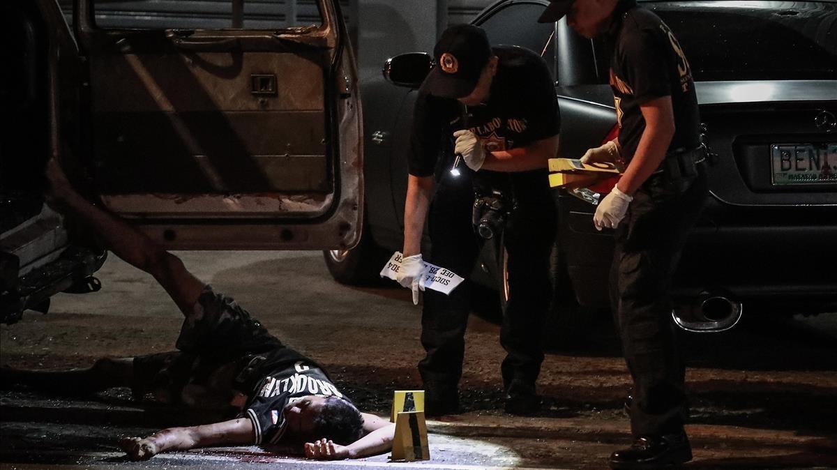 Un cadáver junto a un vehículo acribilladoen Manila. Un cadáver junto a un vehículo acribilladoen Manila.
